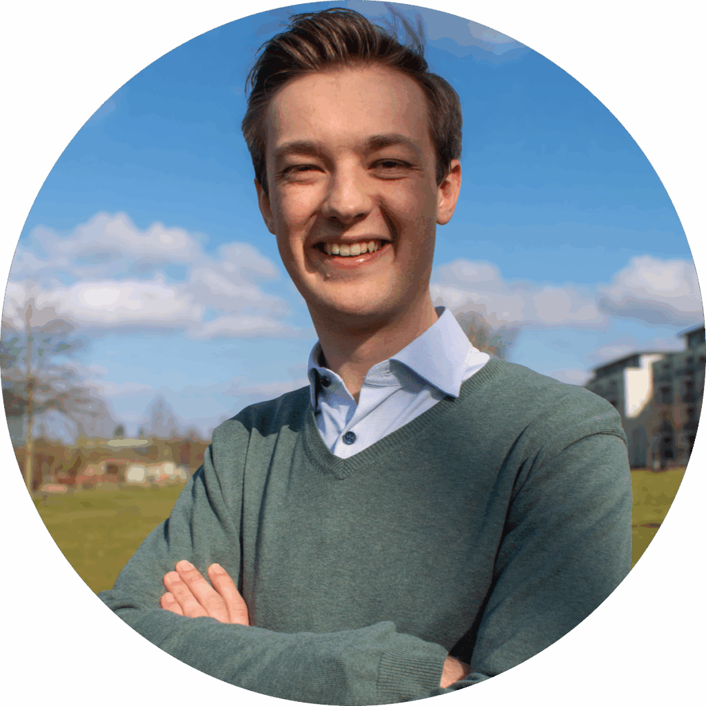 Porträt des Referenten Julian Risse mit kurzem braunem Haar, der lächelnd mit verschränkten Armen im Freien steht.